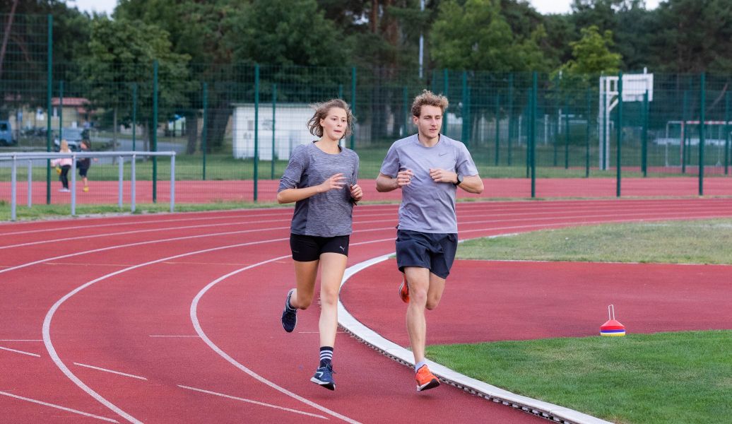 Eine Frau und ein Mann joggen auf der Tartanbahn